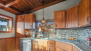 A kitchen with wooden cabinets, a stone backsplash, and a built-in dishwasher. - The Eagles Nest – Couples Escape - Hot Tub & Views! (Ellicottville)