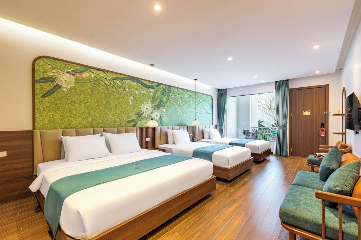 A hotel room with three beds, a sofa, and a large window.