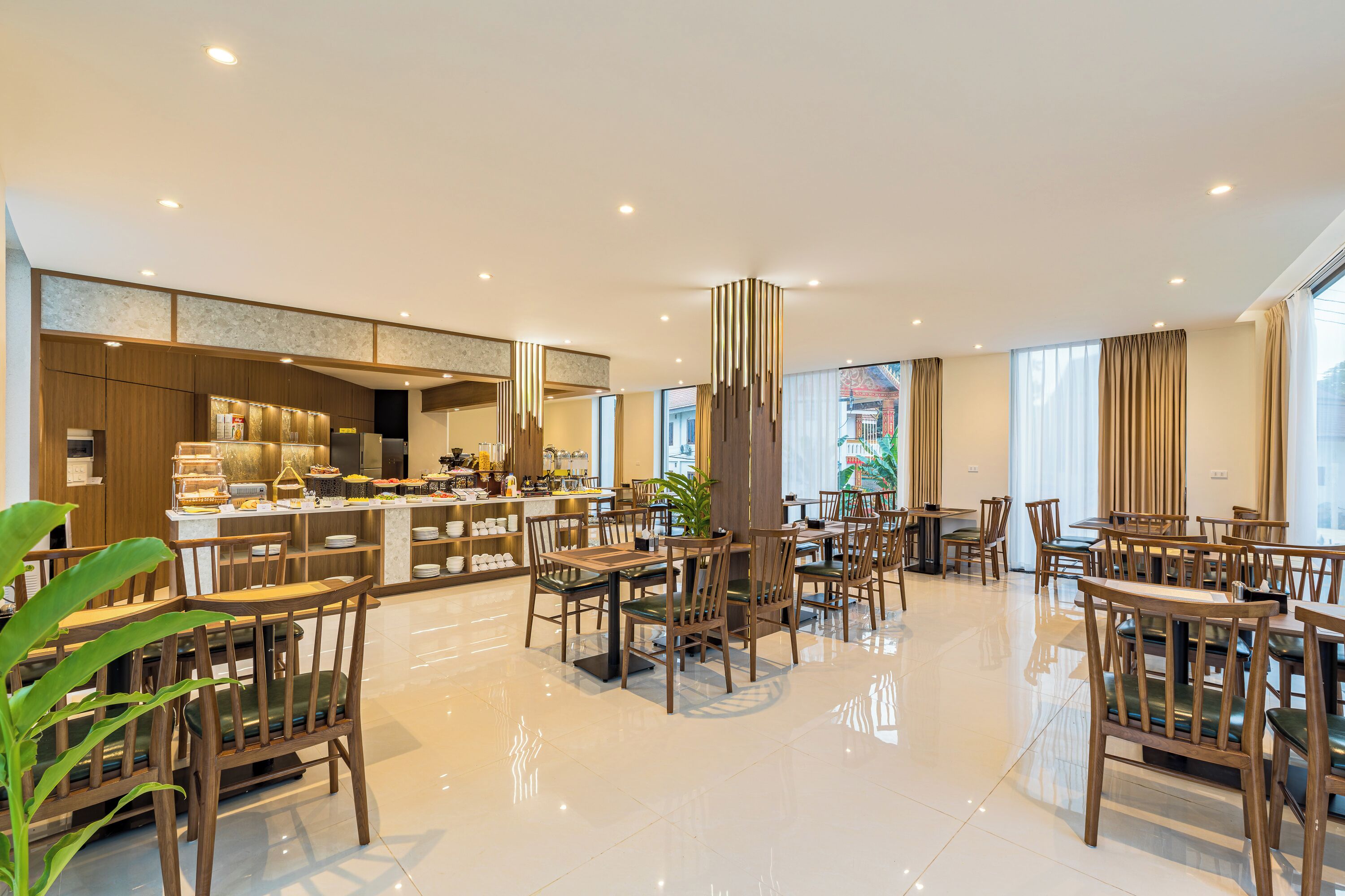 A spacious hotel lobby with a central bar area, multiple seating arrangements, and large windows providing natural light.