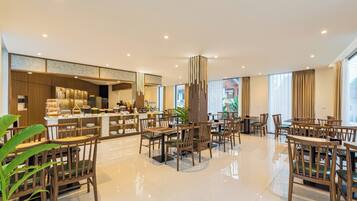 A spacious hotel lobby with a central bar area, multiple seating arrangements, and large windows providing natural light.