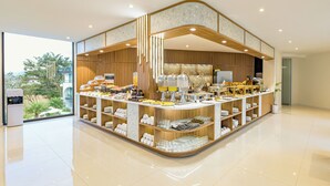 A modern breakfast bar with a curved design, featuring a variety of breakfast items and glassware. - Sunrise Mountain View Resort (Vang Vieng)