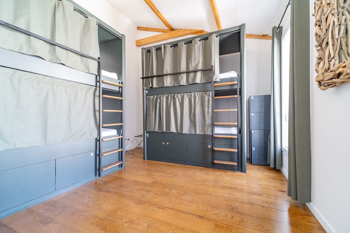 Une chambre avec un lit superposé, des rangements intégrés et un plafond en bois.