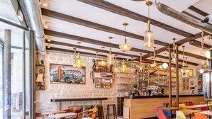 A cozy cafe with exposed wooden beams, a stone wall, and a bar area. - FRATERNITY-HOTEL (Paris)