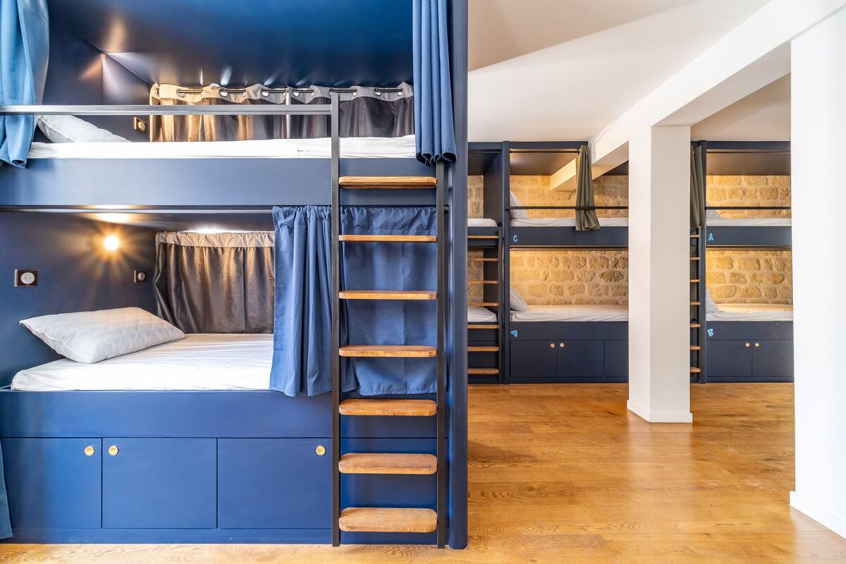 Une chambre avec un lit superposé, une échelle, des étagères en bois et une armoire.