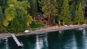 A lakeside cabin with a dock extending into the water, surrounded by dense forest. - Homewood Lakefront by AvantStay | Private Beach & Lake Access + Views! (Homewood)