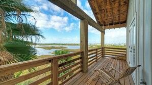 Eine Holzterrasse mit Blick auf einen Fluss und Palmen.