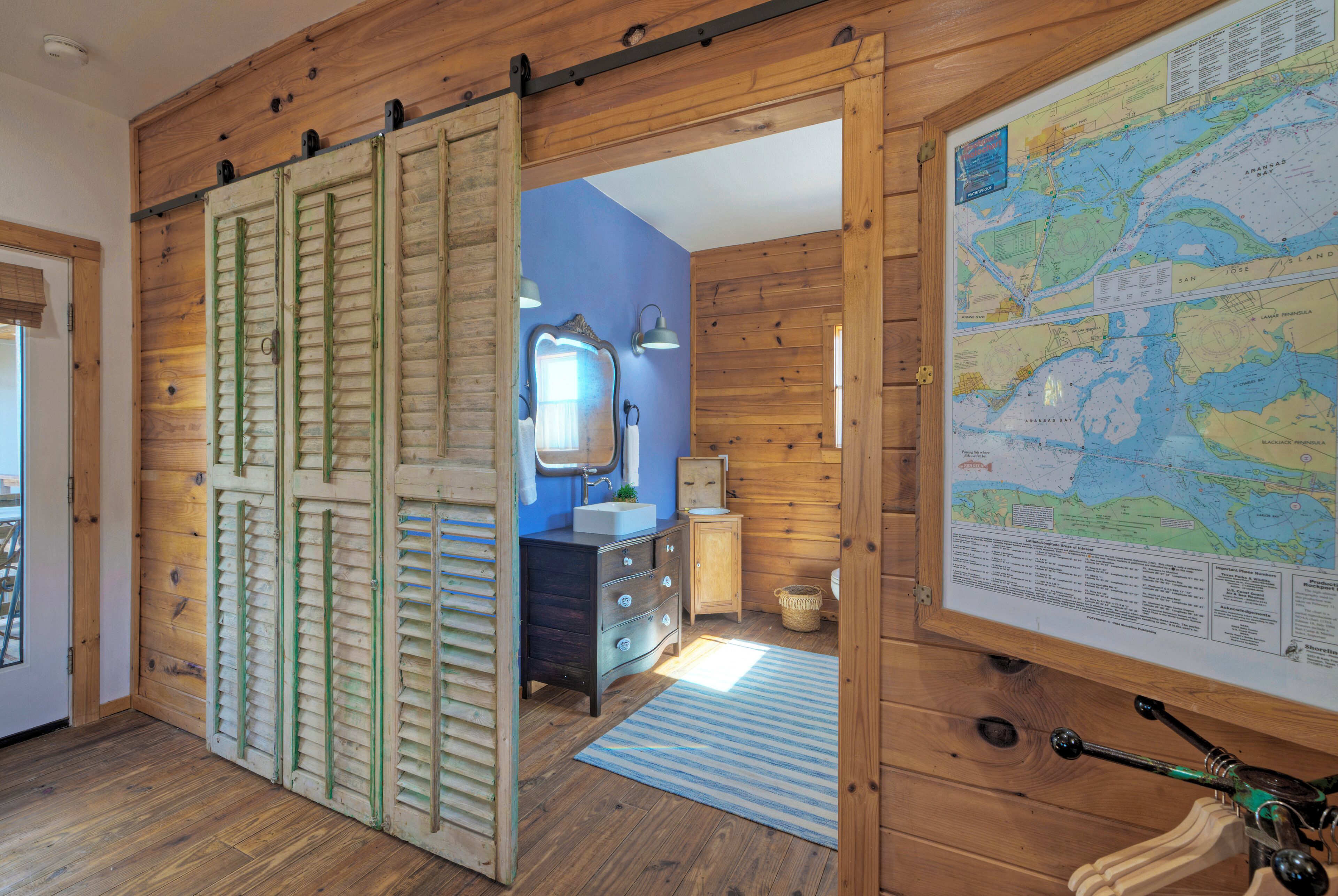 A wooden interior with a sliding door, a map on the wall, a sink, and a mirror.