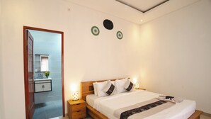 Un dormitorio con una cama de madera, mesitas de noche y un baño visible a través de una puerta abierta.