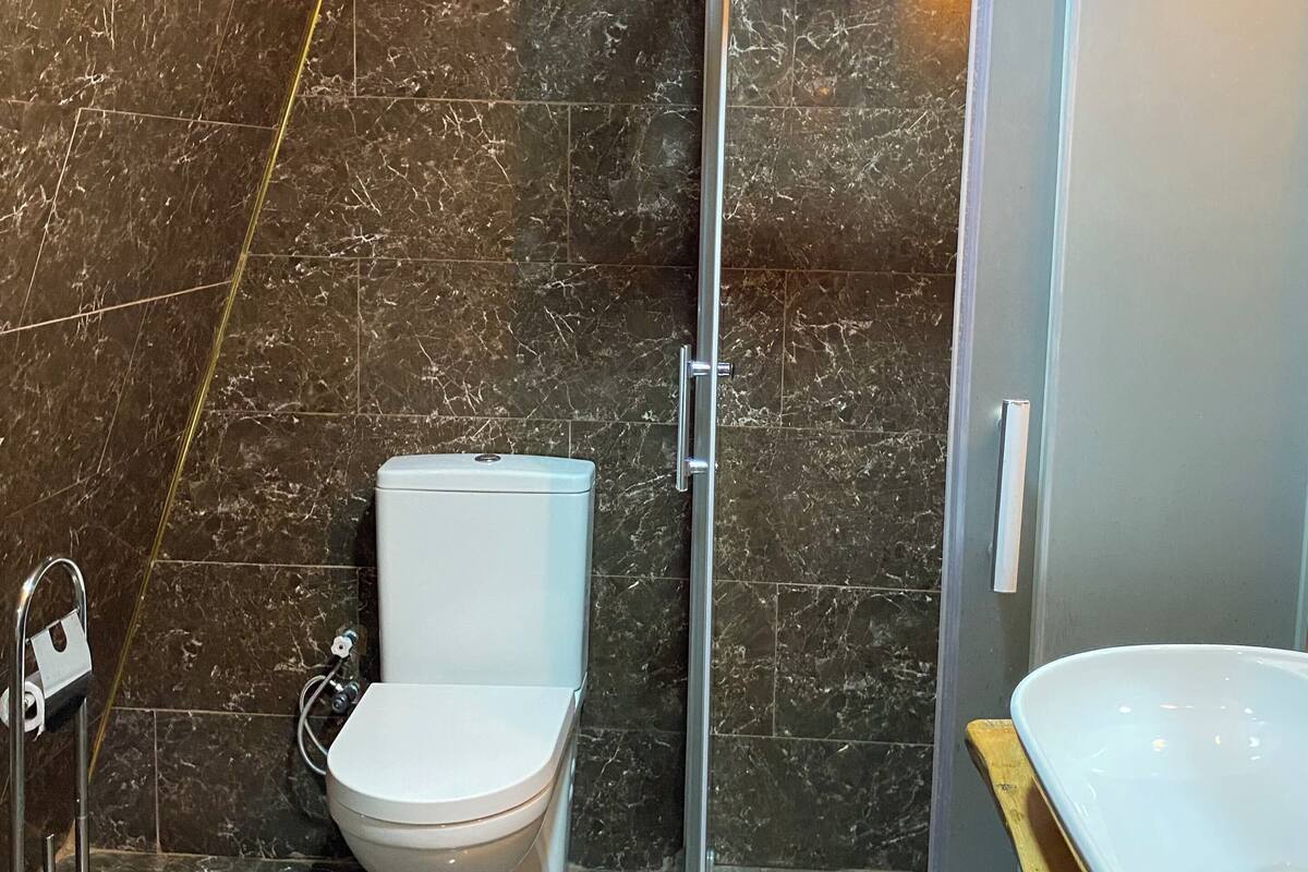 A bathroom with a toilet, a shower enclosure, and a sink.