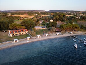 A coastal property with a beach, boats, and a large building with multiple levels. - ASTROIA HOTEL (Lapseki)