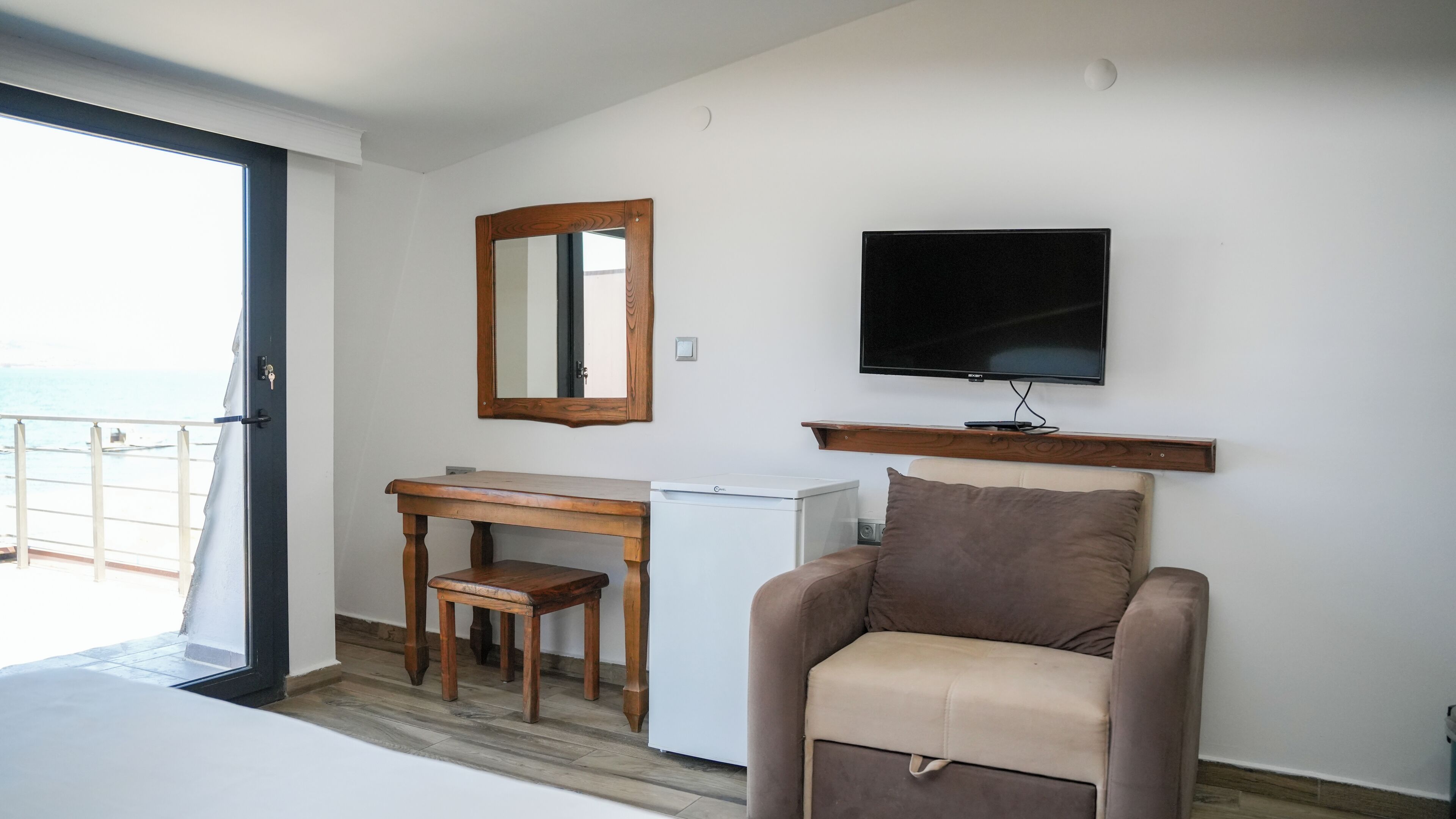 Een kamer met een bureau, stoel, televisie en uitzicht op zee.