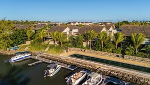 A marina with boats docked, surrounded by houses with sloped roofs and palm trees. - La Balise Marina by Horizon Holidays (Black River)