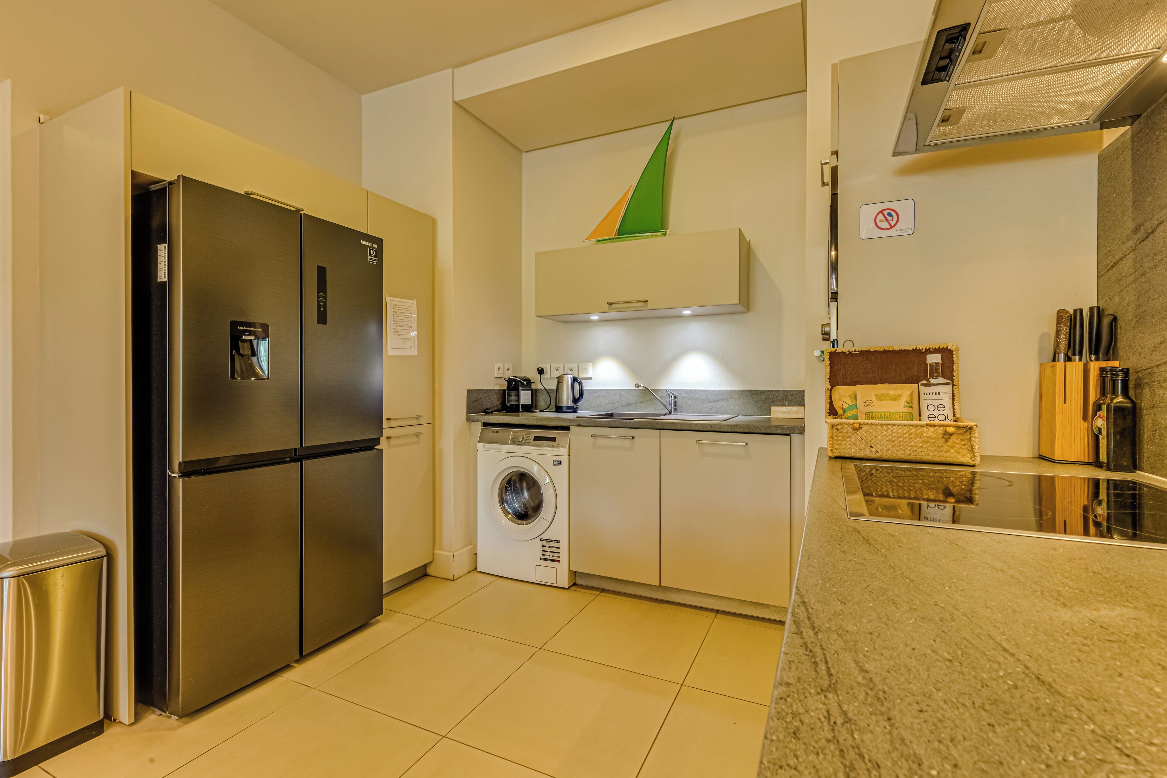 A compact kitchen with a stainless steel refrigerator, a built-in washing machine, and a microwave.