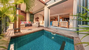 A swimming pool with wooden decking, wicker furniture, and a view into a modern interior space. - La Balise Marina by Horizon Holidays (Black River)