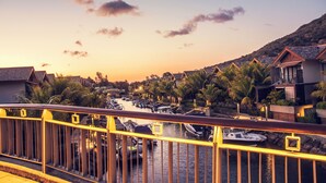 A marina with boats docked, a bridge with yellow railings, and houses with sloped roofs. - La Balise Marina by Horizon Holidays (Black River)