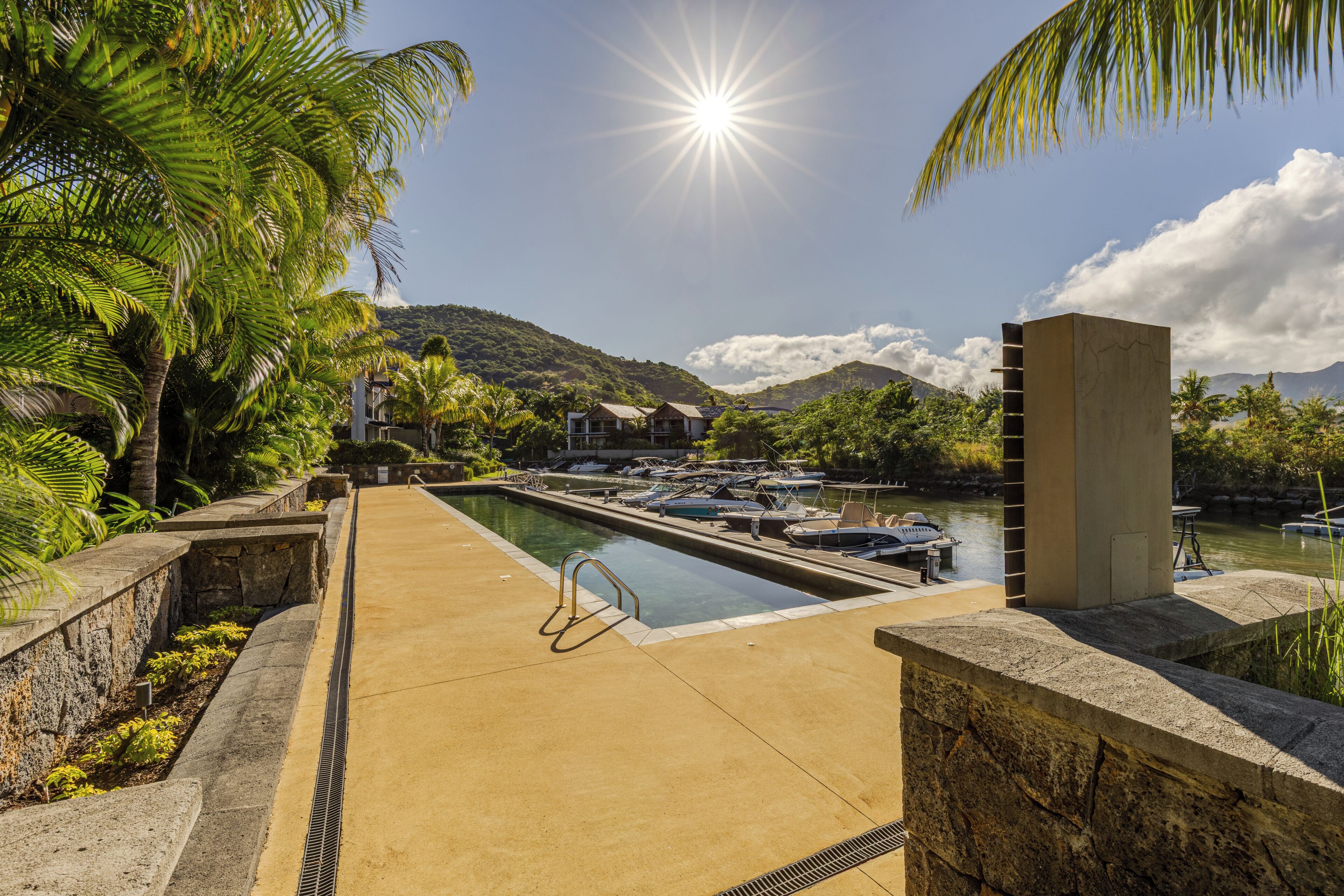 A swimming pool with a view of boats and a mountain in the background.
