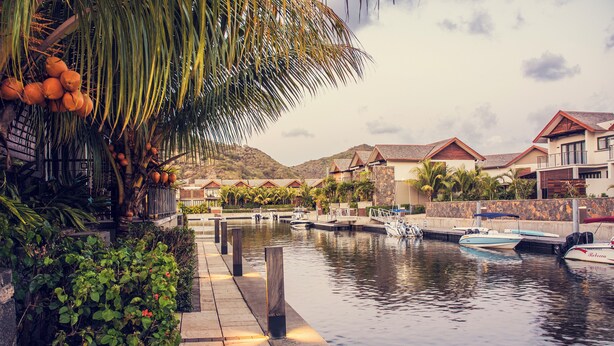 A waterfront property with a dock, boats, and a row of houses with red roofs. - La Balise Marina by Horizon Holidays (Black River)