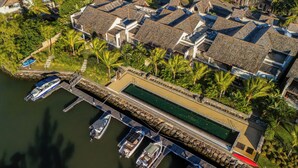 An aerial view of a coastal resort with multiple villas, a swimming pool, and a dock with boats. - La Balise Marina by Horizon Holidays (Black River)