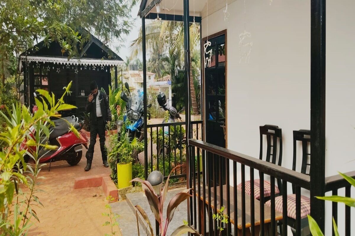 A covered outdoor area with a seating arrangement, a small structure with a roof, and a scooter parked nearby.