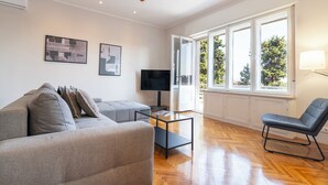 A modern living room with a grey sofa, a glass coffee table, a TV, and a chair. - Sun Spalato Firule (Split)