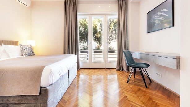 A hotel room with a bed, a desk, a chair, and a large window with curtains. - Sun Spalato Firule (Split)