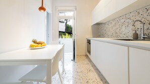A modern kitchen with white cabinetry, a speckled backsplash, and a stainless steel sink. - Sun Spalato Firule (Split)