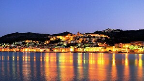 A coastal town at dusk with buildings illuminated against a darkening sky, reflecting on calm waters. - Double room 1 with separate entrance (Cariati)
