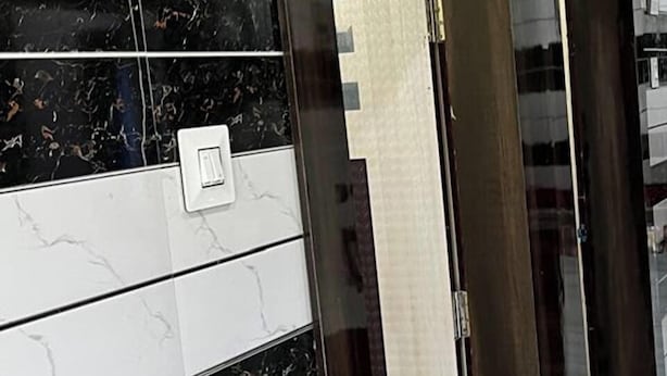 A modern interior with a black and white tiled wall, a door, and a light switch. - Sindura Lodge (Gop)