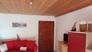 A room with a red sofa, a wooden cabinet, a television, and a door. - Vacation apartment Hirschgwai 50sqm with balcony (Oberaudorf)