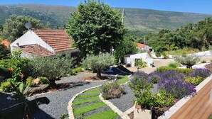 A residential area with houses, a large tree, and a garden with purple flowers. - Luxe & Charme Résidence (Porto de Mos)