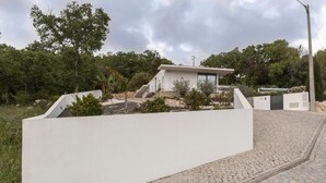 A modern house with a white exterior, a paved driveway, and a garden area with trees and shrubs. - Luxe & Charme Résidence (Porto de Mos)