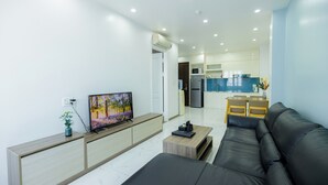 Ein modernes Wohnzimmer mit einer schwarzen Ledersofa, einem Flachbildfernseher und einem Holztischchen.
