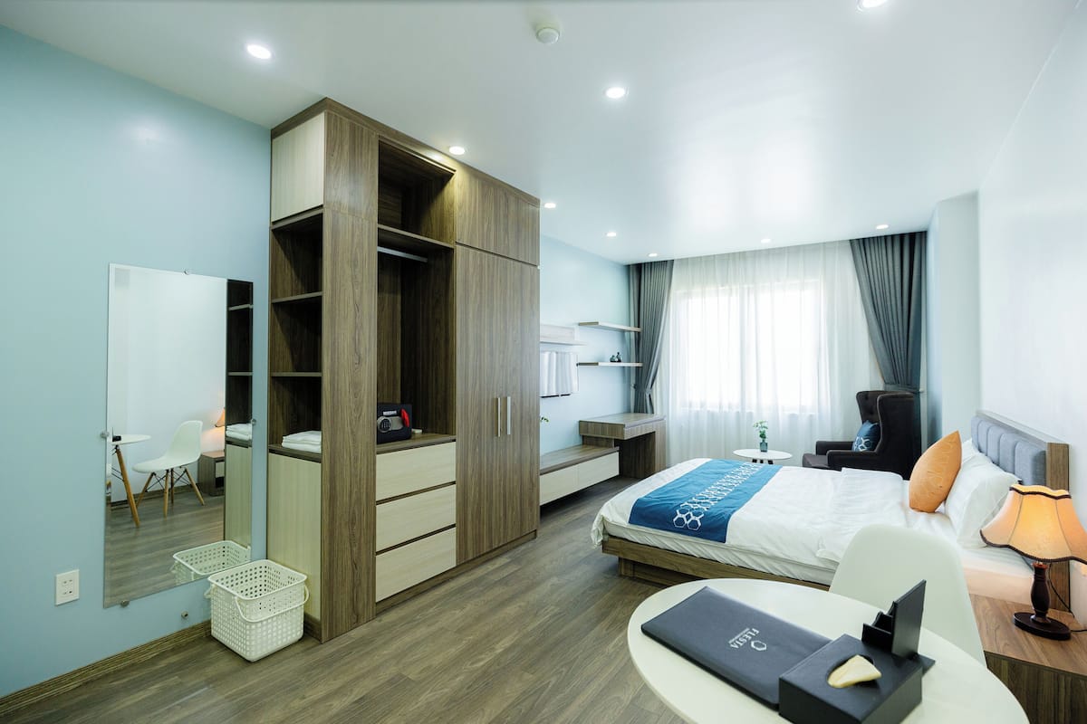 Une chambre d’hôtel moderne équipée d’un grand lit, d’un bureau, d’une chaise, d’une armoire et d’un miroir.
