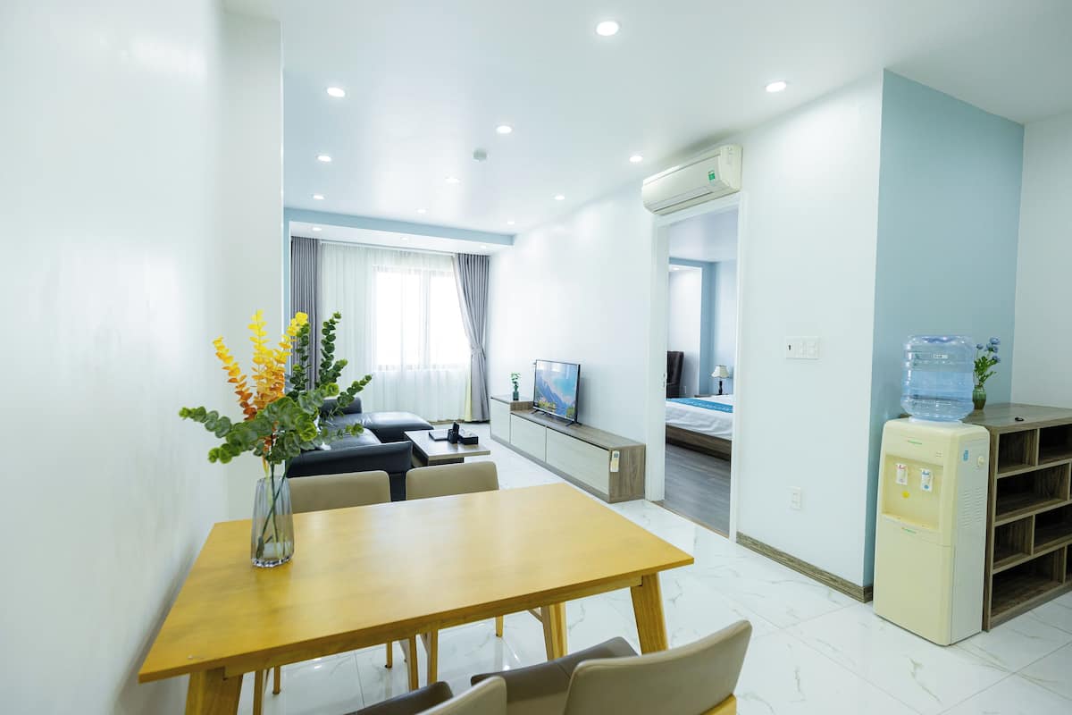 Une chambre d’hôtel moderne équipée d’un coin repas, d’un canapé, d’une télévision et d’un distributeur d’eau.