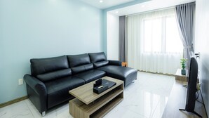 Ein modernes Wohnzimmer mit einer schwarzen Ledersofa, einem Holztisch und einem Flachbildfernseher.