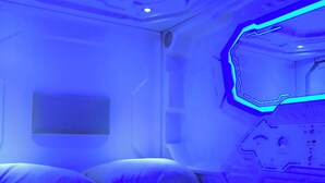 A room with a bed, a wall-mounted control panel, and a ceiling with recessed lighting. - Capsule hostel Floor -1 Self Check in (Warsaw)
