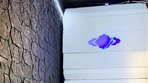 A room with a textured wall and a white cabinet with a purple logo. - Capsule hostel Floor -1 Self Check in (Warsaw)