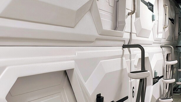 A row of white, modern-looking lockers with handles and a control panel, likely for storing personal items. - Capsule hostel Floor -1 Self Check in (Warsaw)