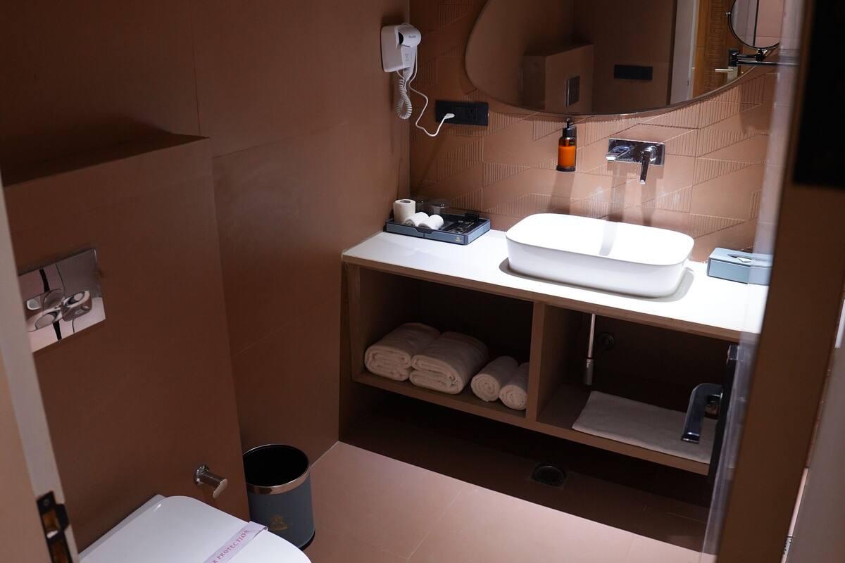 A compact bathroom with a white toilet, a sink, and a mirror.