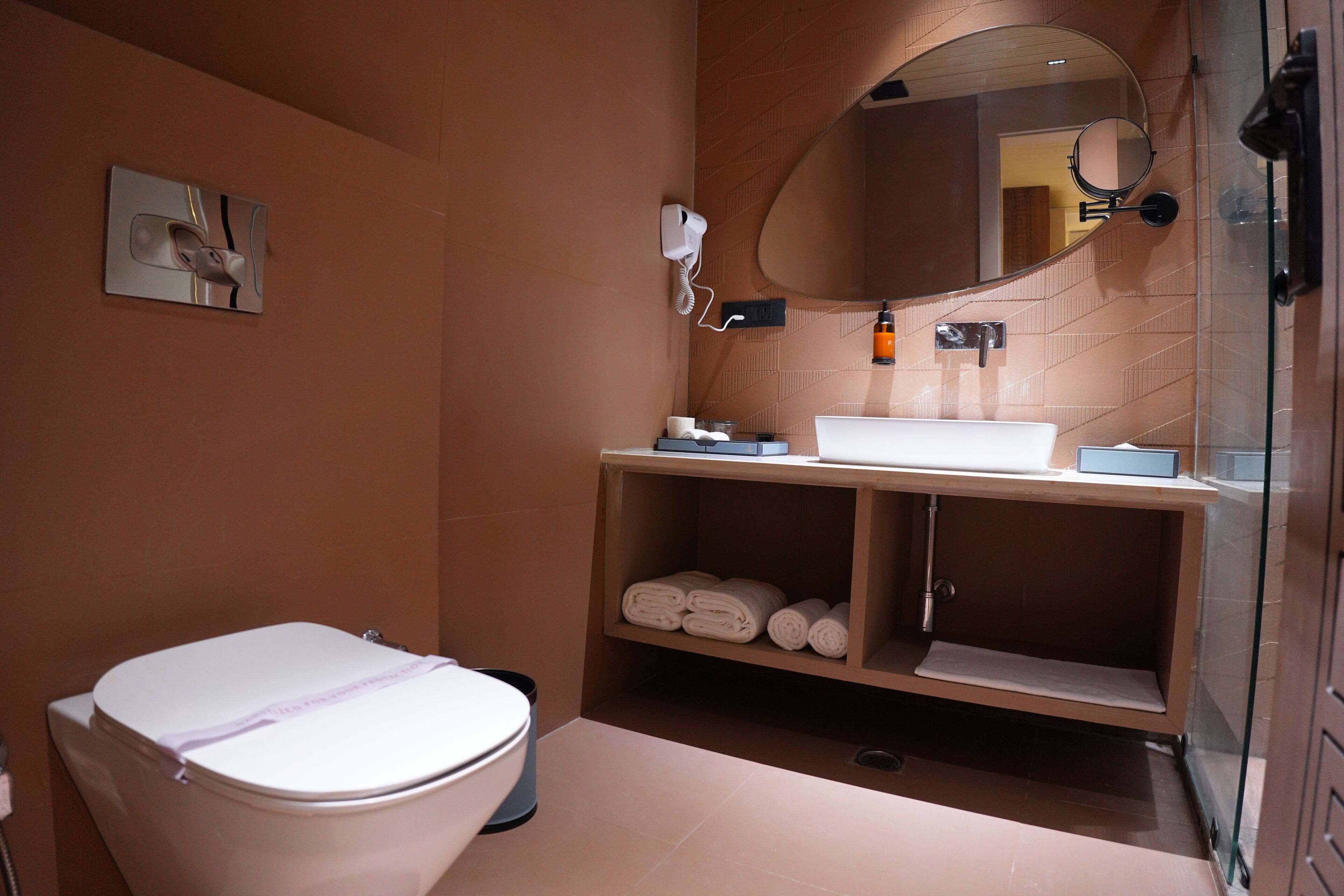 A bathroom with a toilet, a sink, a mirror, and a towel rack.