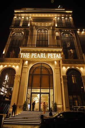 A building with the sign "THE PEARL PETAL" at the entrance, featuring large arched windows and a grand staircase leading up to the door. - The Pearl Petal (Rohtak)
