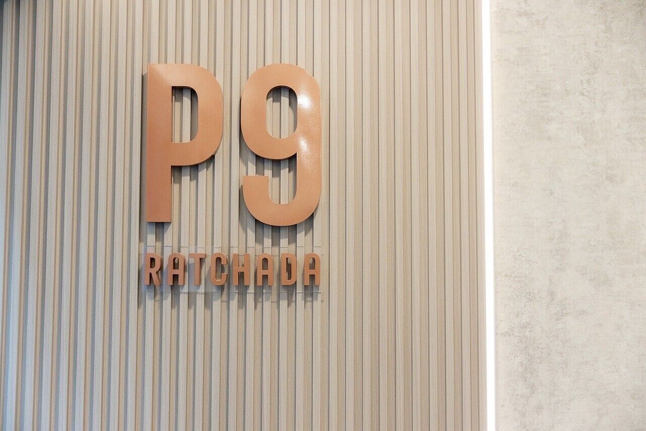 A sign with the letters "P9" and the word "RATCHADA" on a textured wall.