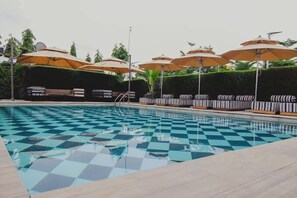 A pool with checkered tiles, lounge chairs, and umbrellas. - ABUS APARTMENT (Asaba)