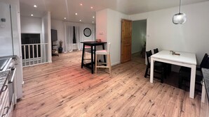 Ein geräumiger Wohnbereich mit Holzboden, einem Esstisch und einer Küchenzeile mit Kühlschrank.