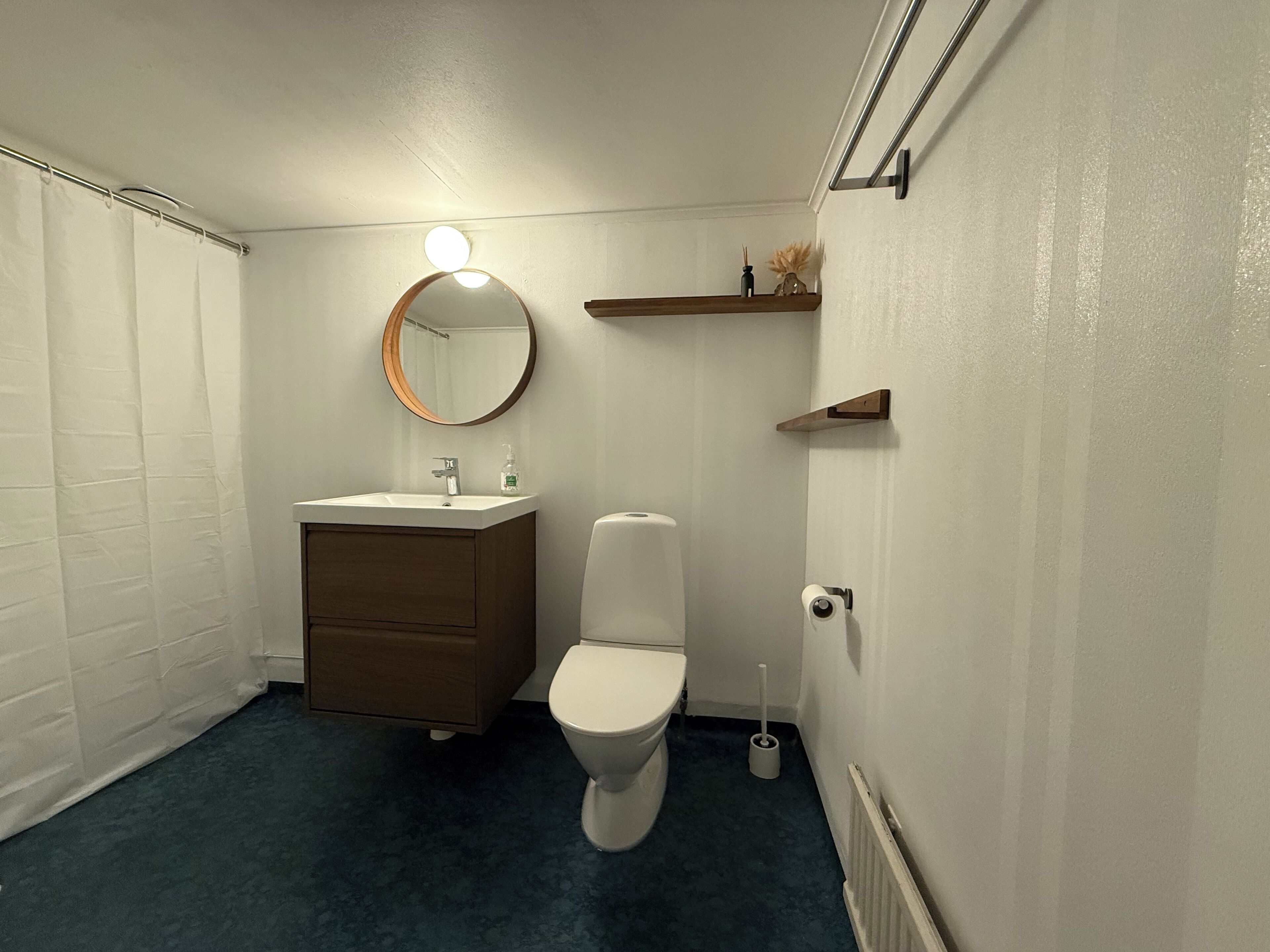 Een badkamer met een wit wastafel, toilet, spiegel en douchegordijn.