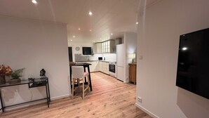 Eine moderne Küche mit Holzboden, einem Essbereich mit Tisch und Stühlen sowie einem großen Flachbildfernseher an der Wand.