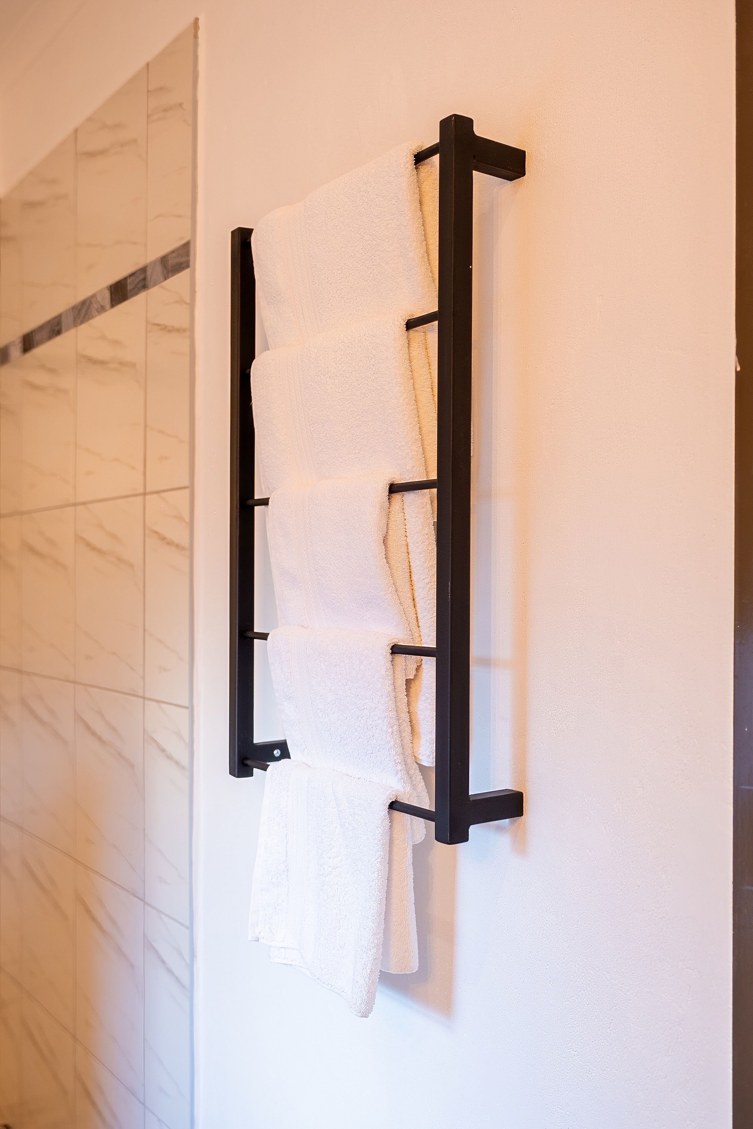 A wall-mounted towel rack with multiple towels.