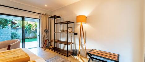 Una habitación de hotel moderna con una cama grande, un banco de madera, una lámpara de pie y un estante negro.