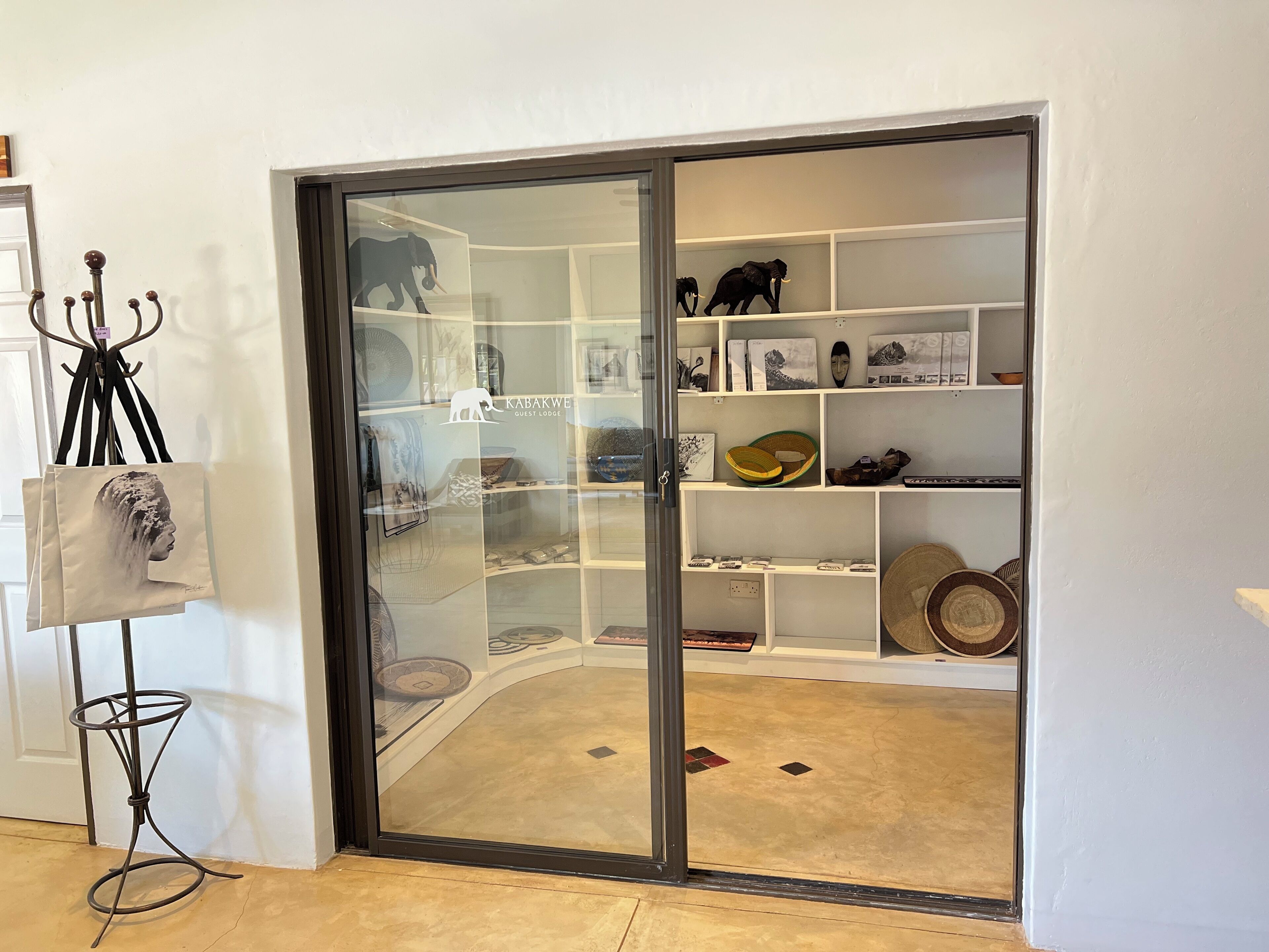 Ein Zimmer mit einer Schiebeglasdoor, die zu einem Stauraum mit Regalen und verschiedenen Gegenständen führt.