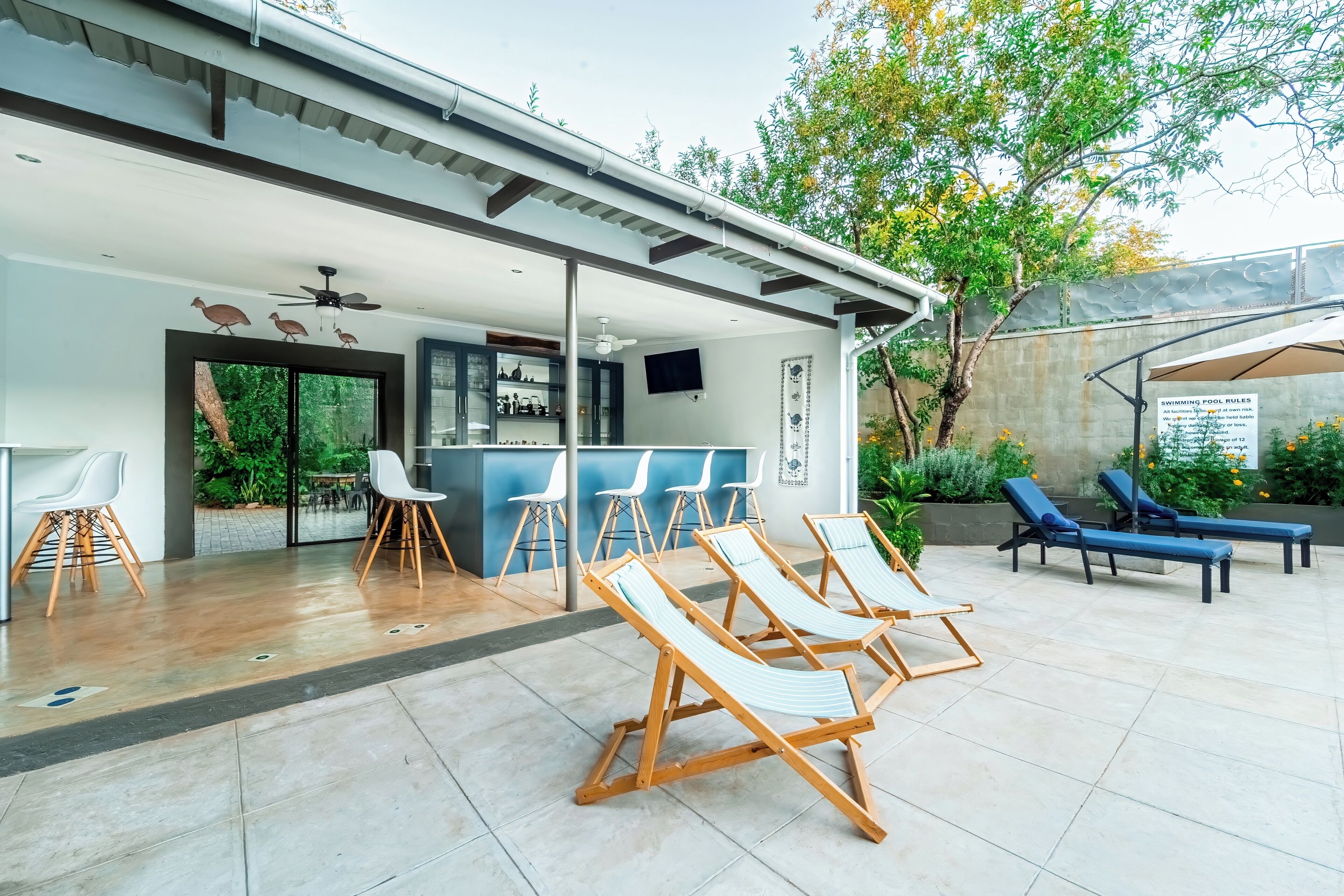 Een modern terras buiten met ligbedden, een poolbar en uitzicht op het zwembad.